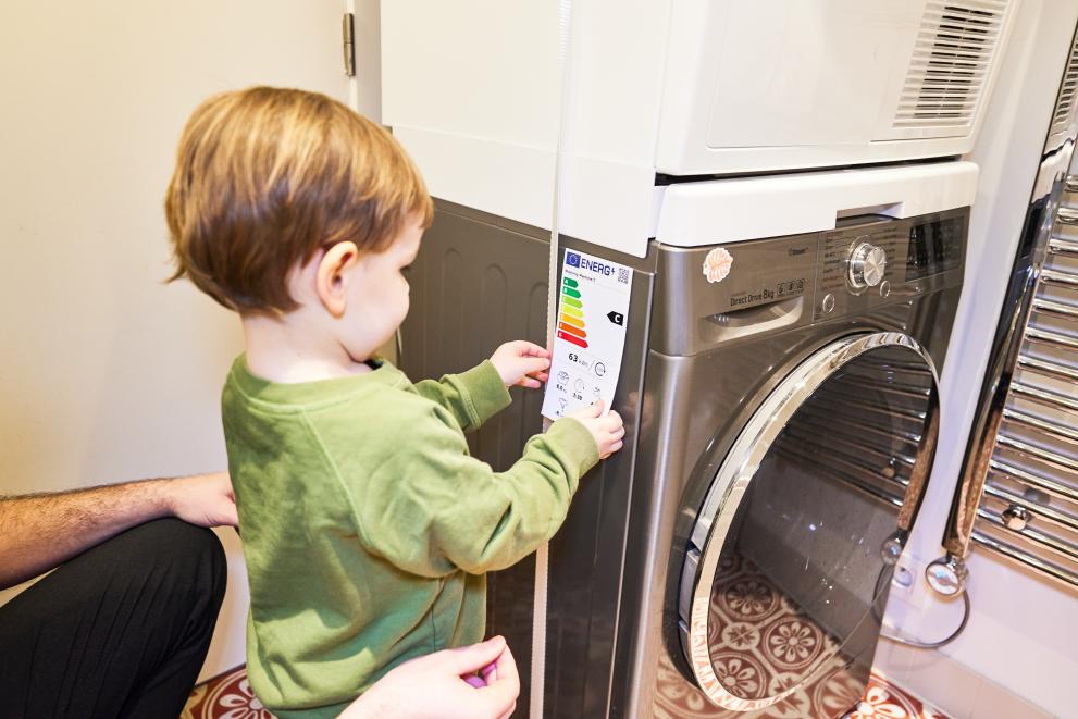 A child putting the new EU energy label with a QR code on a washing machine